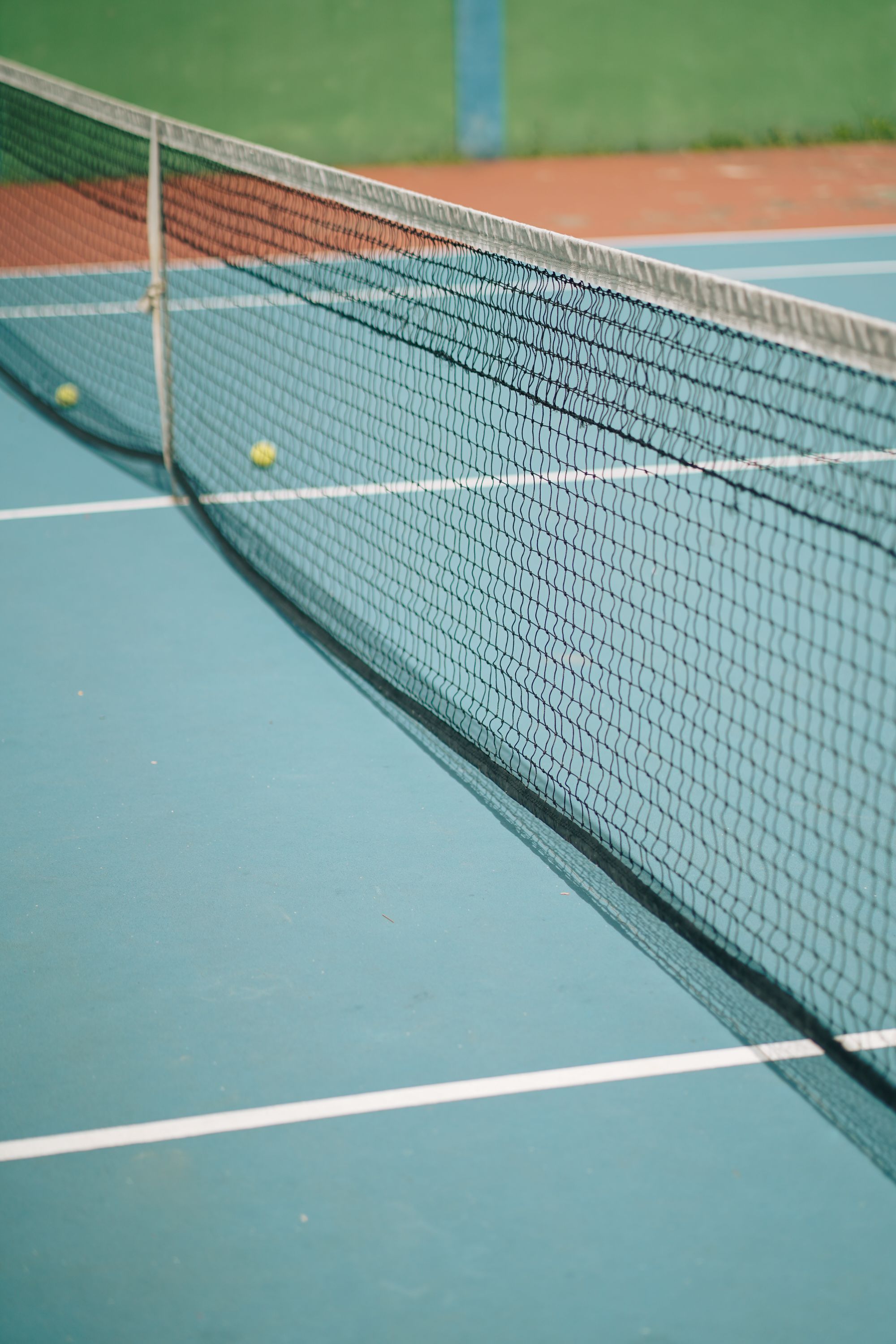 Tennis balls resting beside the net on an empty court